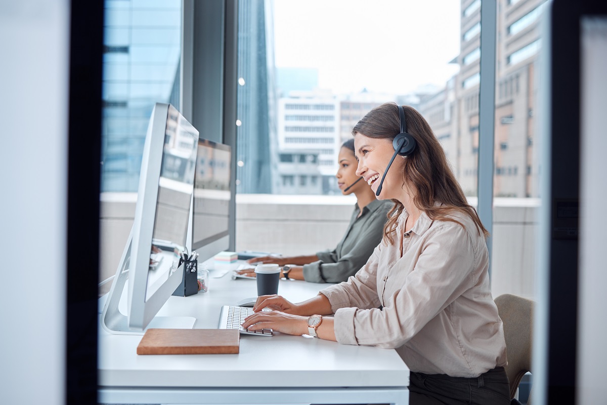 women, office workers, sitting in an office at computers desks, recieving calls from clients